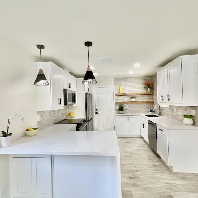 kitchen with stainless steel appliances, white cabinetry, decorative light fixtures, and kitchen peninsula