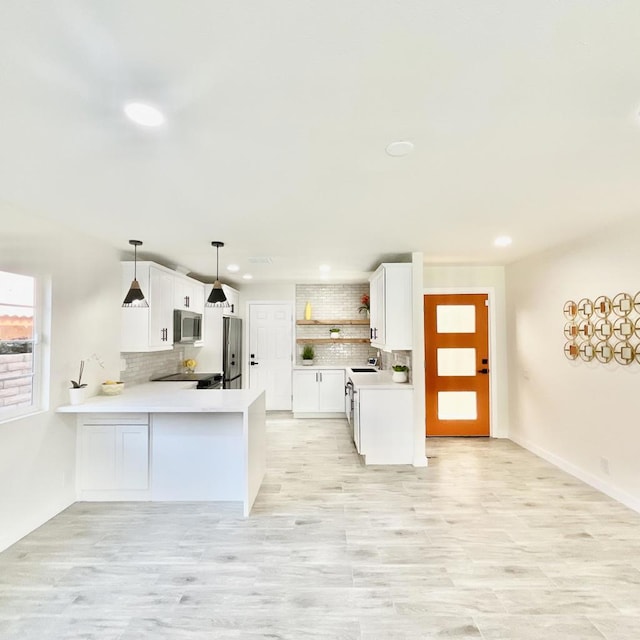 kitchen featuring white cabinetry, pendant lighting, kitchen peninsula, and appliances with stainless steel finishes