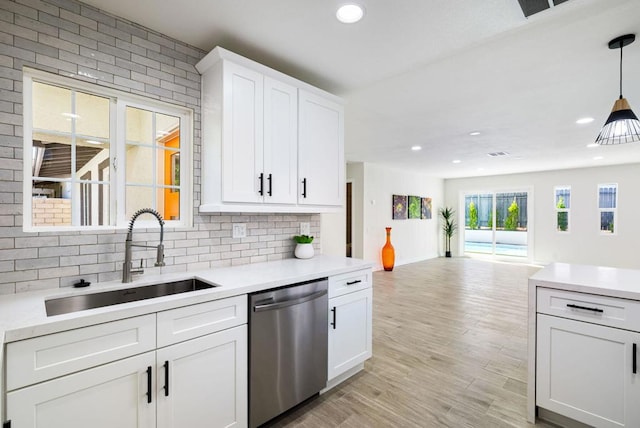 kitchen featuring stainless steel dishwasher, decorative light fixtures, sink, and white cabinets