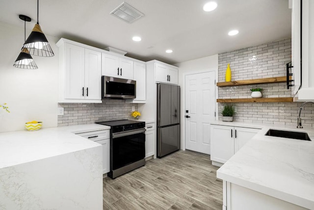 kitchen with hanging light fixtures, white cabinetry, and appliances with stainless steel finishes