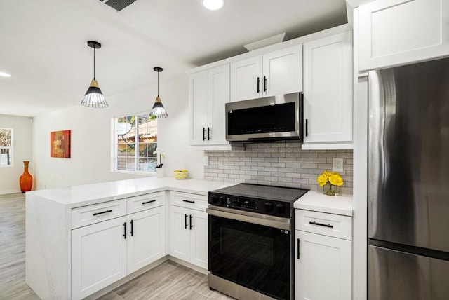 kitchen featuring white cabinetry, hanging light fixtures, kitchen peninsula, and appliances with stainless steel finishes