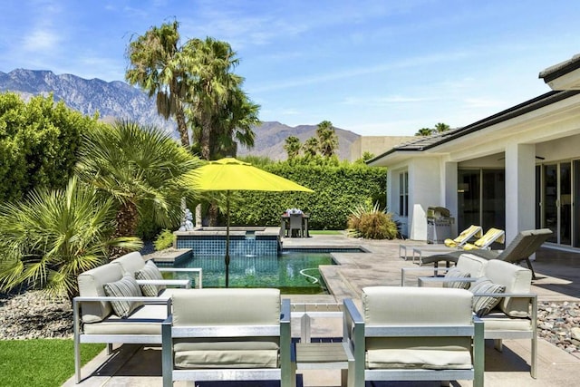 view of swimming pool with outdoor lounge area, a mountain view, and a patio area