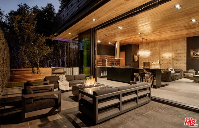 view of patio / terrace with exterior bar and an outdoor living space with a fire pit