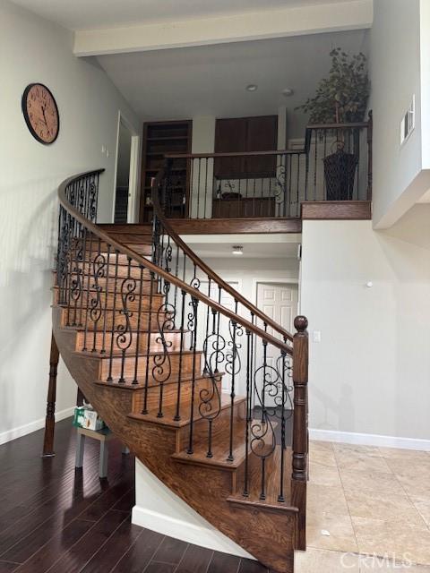 stairway with beam ceiling, wood-type flooring, and a high ceiling