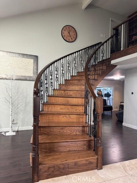 stairs with beamed ceiling, wood-type flooring, and high vaulted ceiling