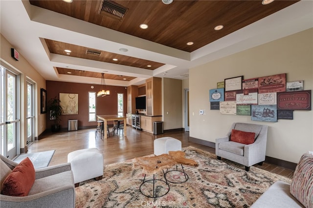 living room with a wealth of natural light, wooden ceiling, a raised ceiling, and light wood-type flooring