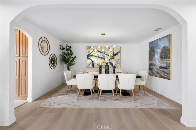 dining space featuring light hardwood / wood-style flooring and a notable chandelier