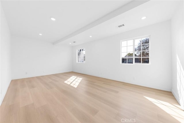 empty room with beamed ceiling and light wood-type flooring