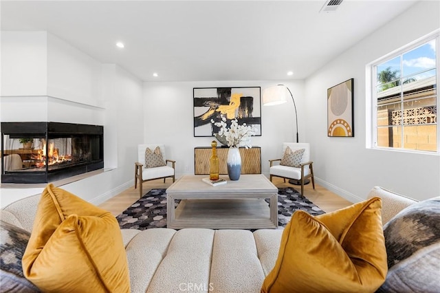 living room with light hardwood / wood-style floors and a multi sided fireplace