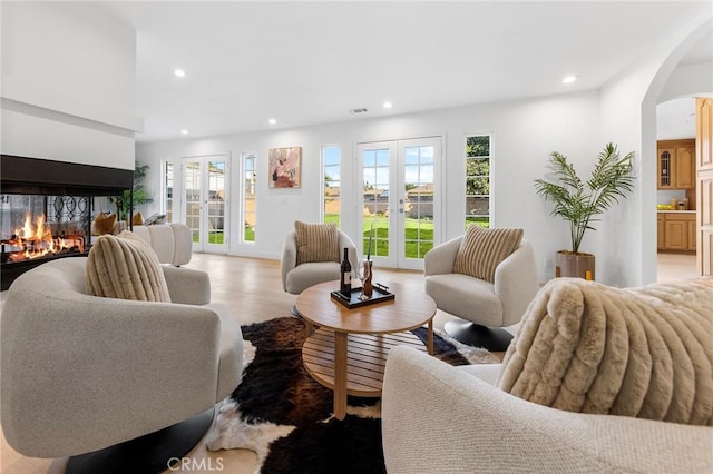 living room featuring light hardwood / wood-style floors, a multi sided fireplace, and french doors