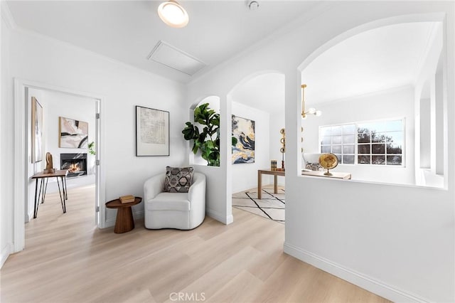 living area featuring light wood-type flooring, crown molding, and an inviting chandelier