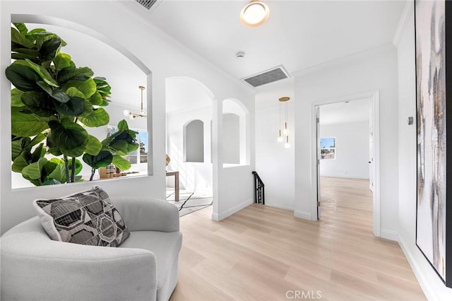 living area with plenty of natural light, ornamental molding, and light hardwood / wood-style flooring