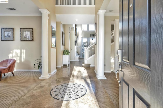 carpeted foyer entrance featuring crown molding and decorative columns