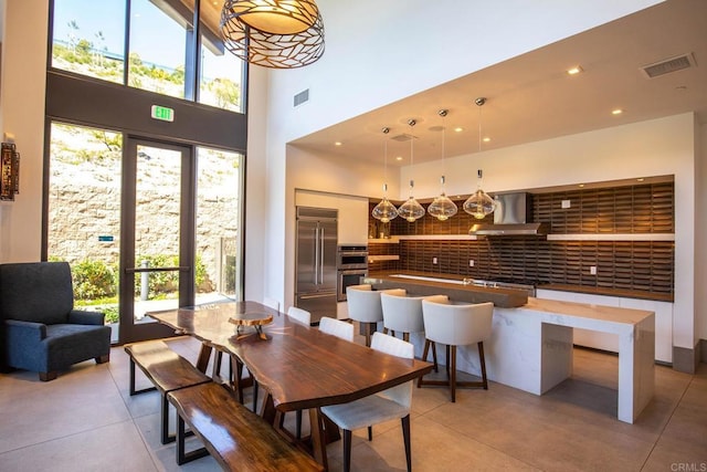 dining space with a high ceiling, plenty of natural light, and visible vents