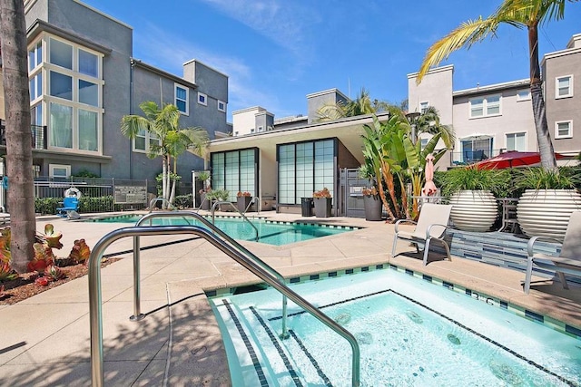 community pool featuring a patio area, fence, and a hot tub