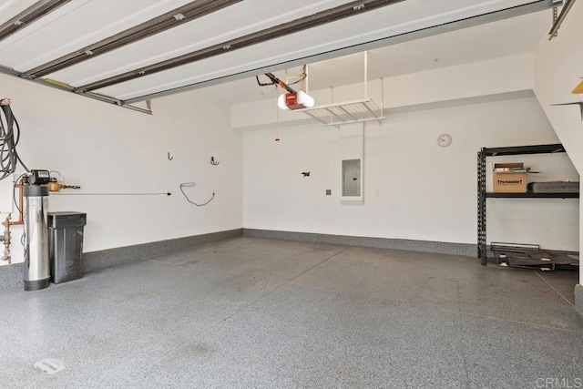 garage featuring electric panel, baseboards, and a garage door opener