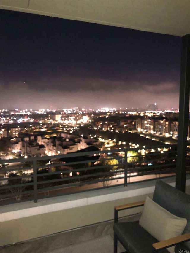 balcony at night featuring a view of city lights