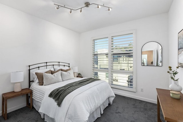 carpeted bedroom with rail lighting, multiple windows, and baseboards