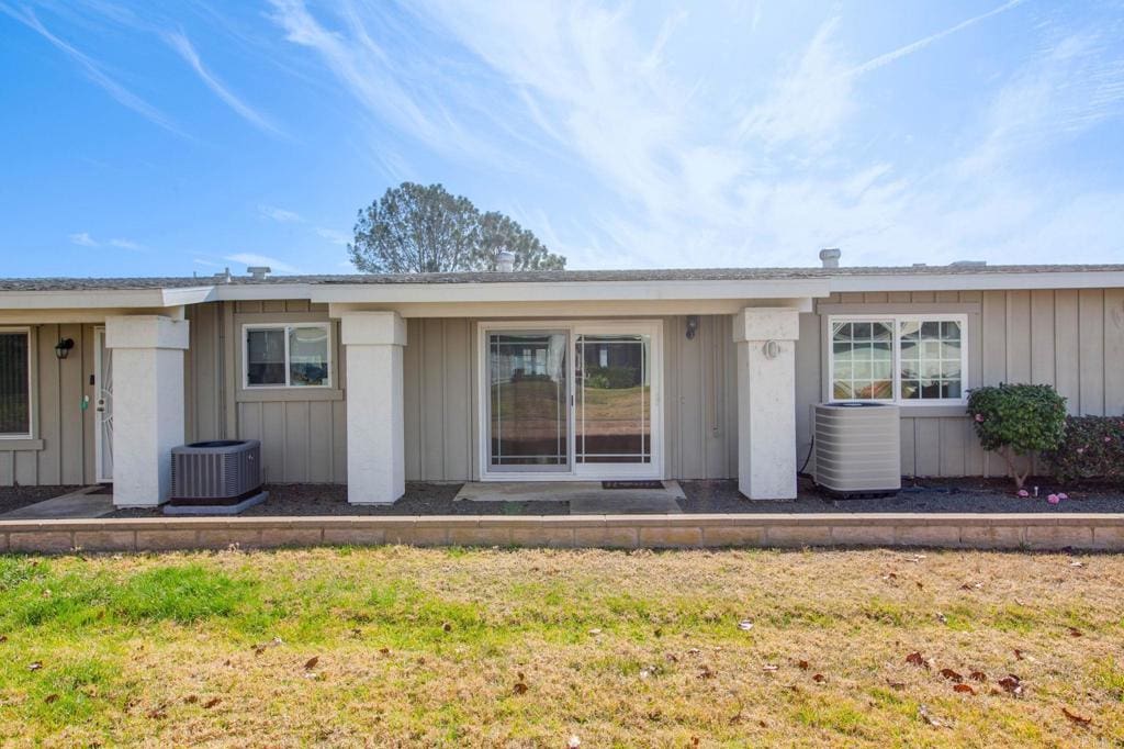 view of exterior entry with a lawn and central air condition unit