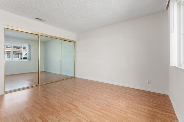 unfurnished bedroom with a closet, a textured ceiling, and light wood-type flooring