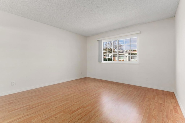 unfurnished room with light hardwood / wood-style flooring and a textured ceiling