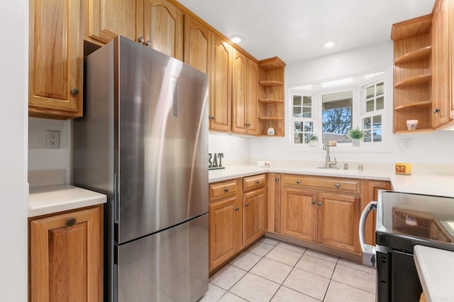 kitchen with stainless steel refrigerator, range with electric stovetop, sink, and light tile patterned floors