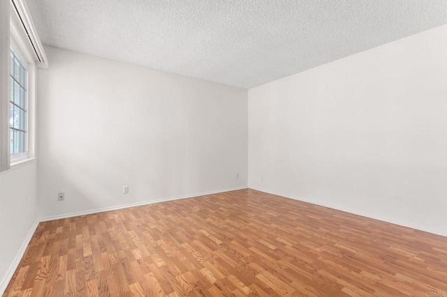 empty room with a textured ceiling and light hardwood / wood-style flooring