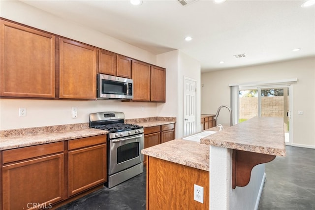 kitchen featuring sink, stainless steel appliances, an island with sink, and a kitchen breakfast bar