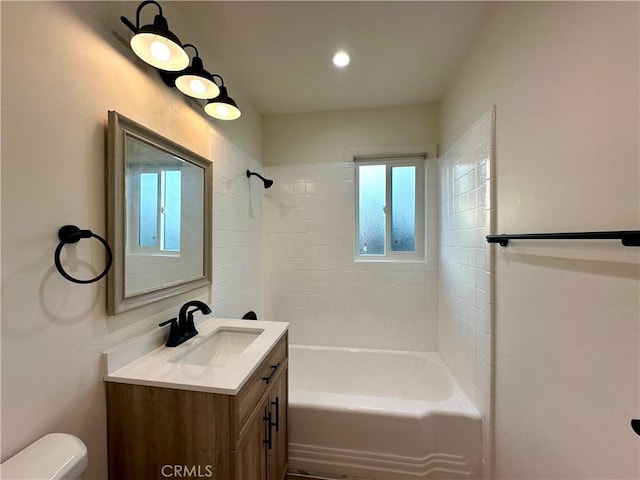 full bathroom with vanity, tiled shower / bath combo, and toilet