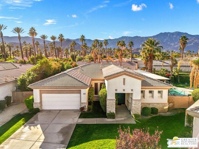 view of front of house featuring a front lawn, a garage, and a mountain view