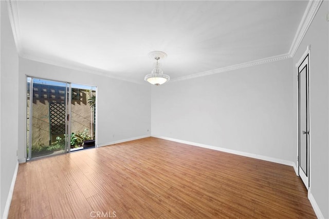 empty room featuring crown molding, wood finished floors, and baseboards