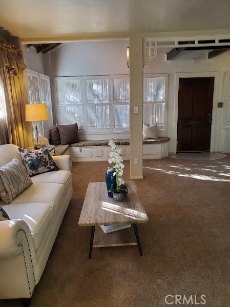 living room featuring beam ceiling and dark colored carpet