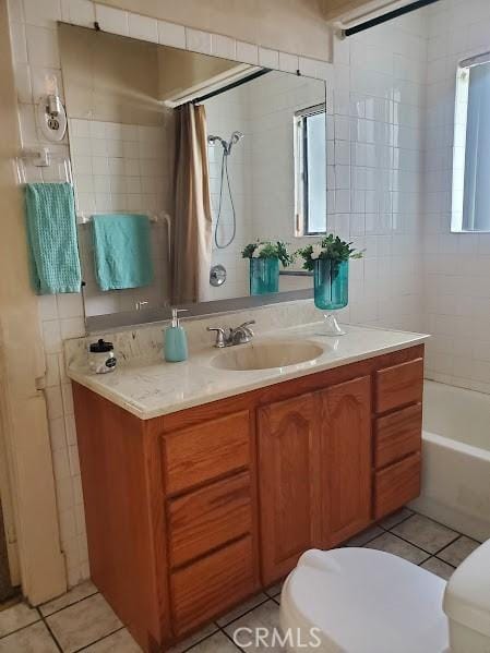 full bathroom featuring toilet, vanity, tile patterned floors, and a wealth of natural light