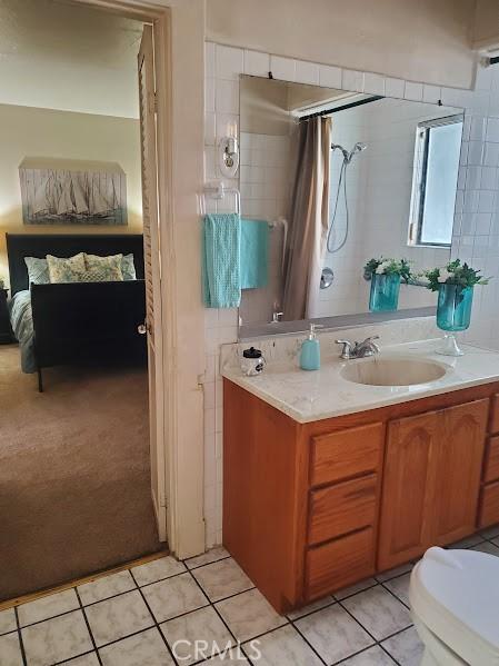 bathroom with toilet, curtained shower, tile patterned floors, and vanity