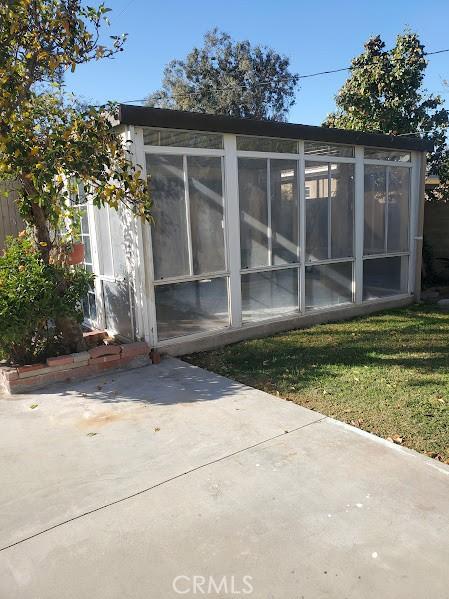 rear view of house featuring a lawn, a patio area, and a sunroom