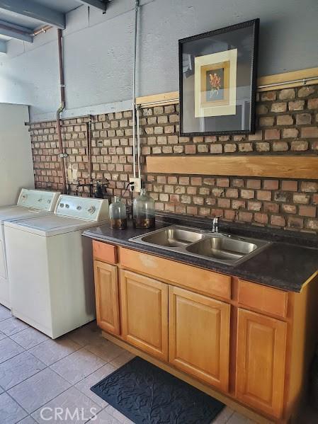 laundry area with washing machine and dryer, light tile patterned floors, and sink