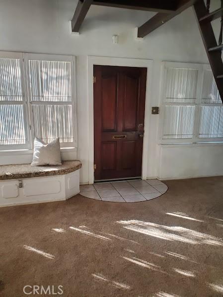 carpeted foyer with beamed ceiling