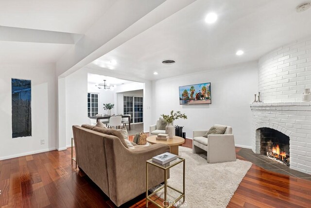 living room featuring a fireplace, dark hardwood / wood-style flooring, and a notable chandelier