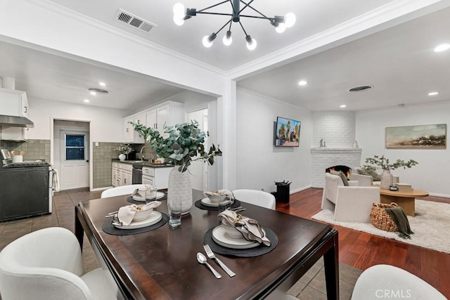 dining room with a fireplace, an inviting chandelier, dark tile patterned floors, and ornamental molding