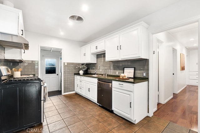 kitchen featuring stainless steel gas range oven, dark tile patterned floors, sink, dishwasher, and white cabinetry