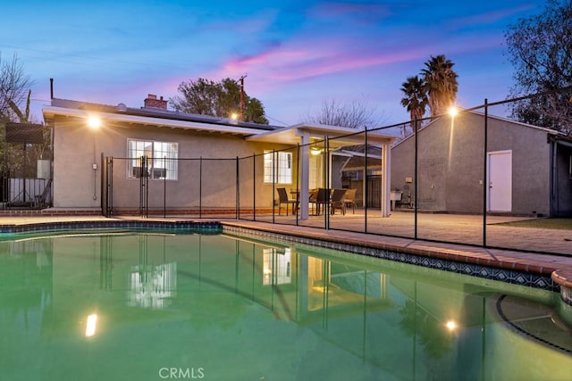 pool at dusk featuring a patio