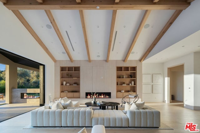 living room featuring lofted ceiling with beams, light hardwood / wood-style floors, and built in features