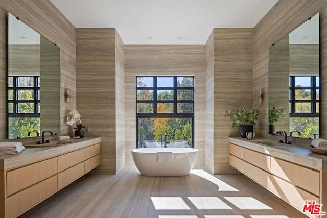 bathroom with a bathtub, vanity, wood-type flooring, and tile walls