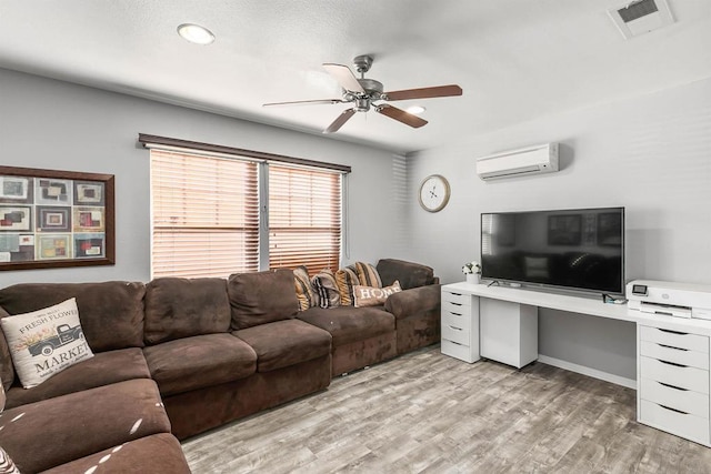 living room featuring an AC wall unit, ceiling fan, and light hardwood / wood-style floors