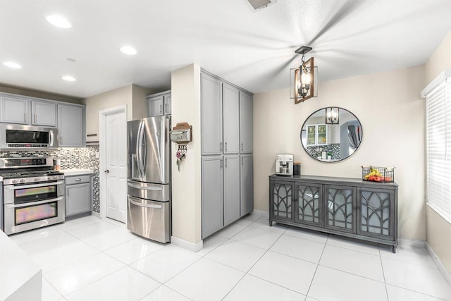 kitchen with decorative light fixtures, gray cabinets, appliances with stainless steel finishes, and tasteful backsplash