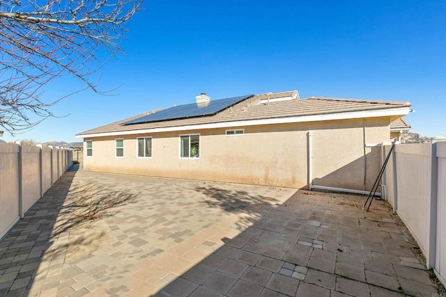 back of property with a patio and solar panels