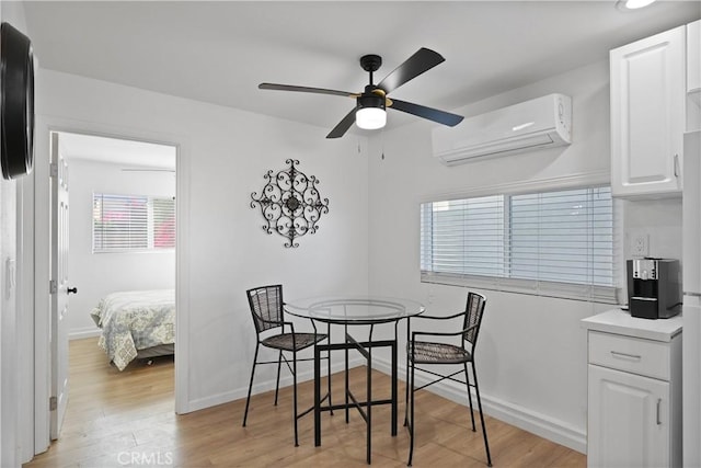 dining area with an AC wall unit, ceiling fan, and light hardwood / wood-style floors