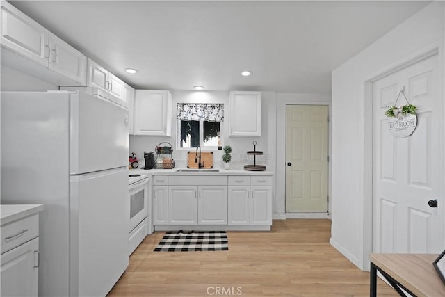 kitchen featuring white cabinetry, sink, and white appliances