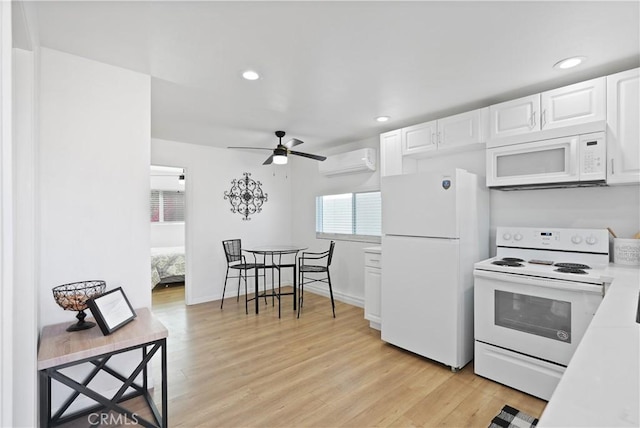 kitchen with light hardwood / wood-style floors, white cabinetry, white appliances, and an AC wall unit