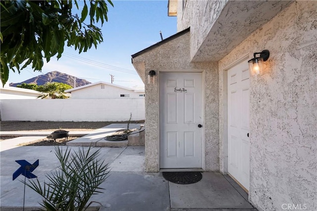 view of exterior entry featuring a mountain view and a patio